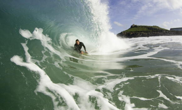 A young man bodyboarding a powerfully wave on the north Cornwall coast on a sunny day.